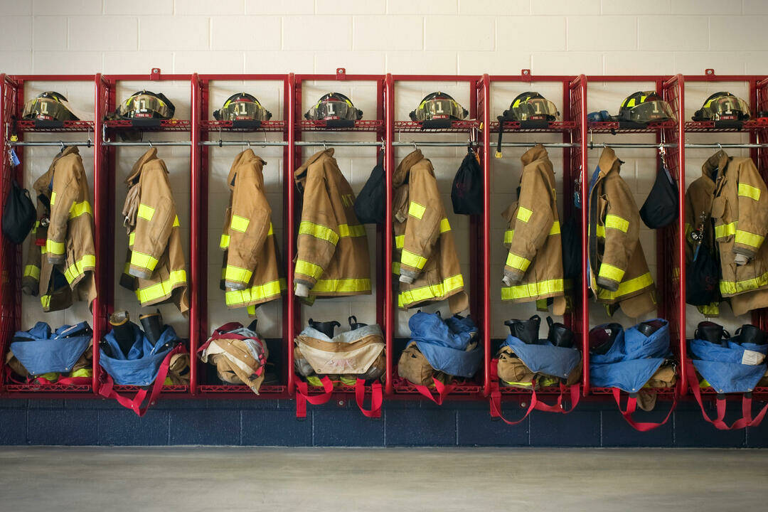 8 Feuerwehruniformen hängend im offenen Spind