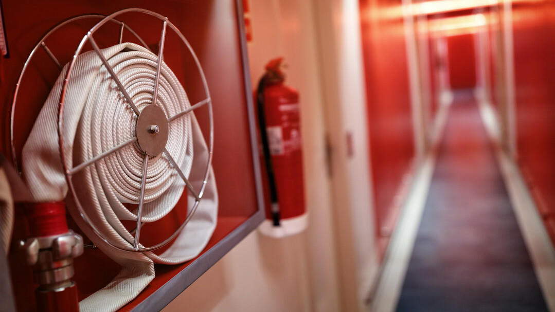 Was macht eine Brandmeldeanlage? Feuerwehrschlauch im Flur