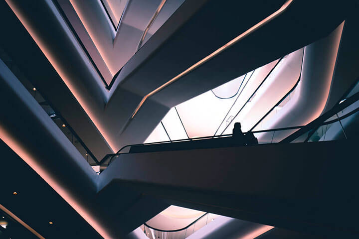 Futuristisches Gebäude mit 2 Menschen auf Rolltreppe