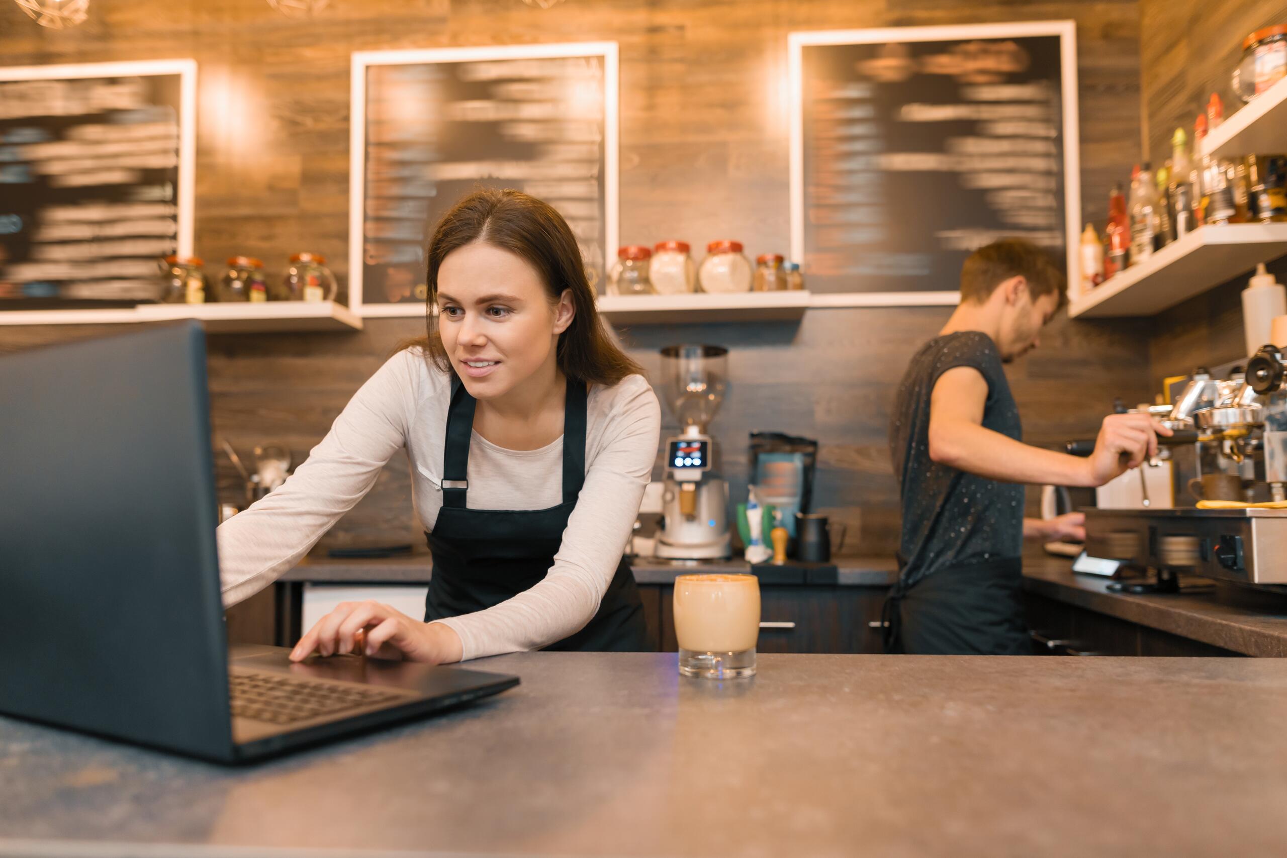 Digitale Schließlösungen für Restaurants & Co. Angestellte im Café mit Laptop