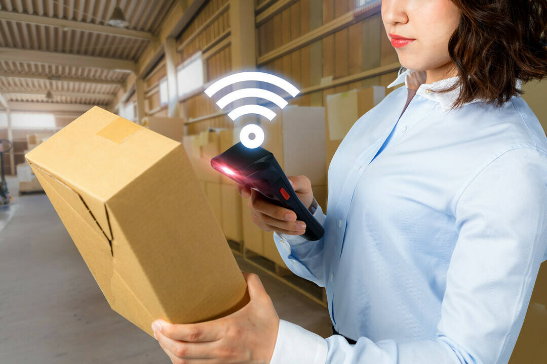 Mitarbeiterin scannt Paket mit RFID-Technologie